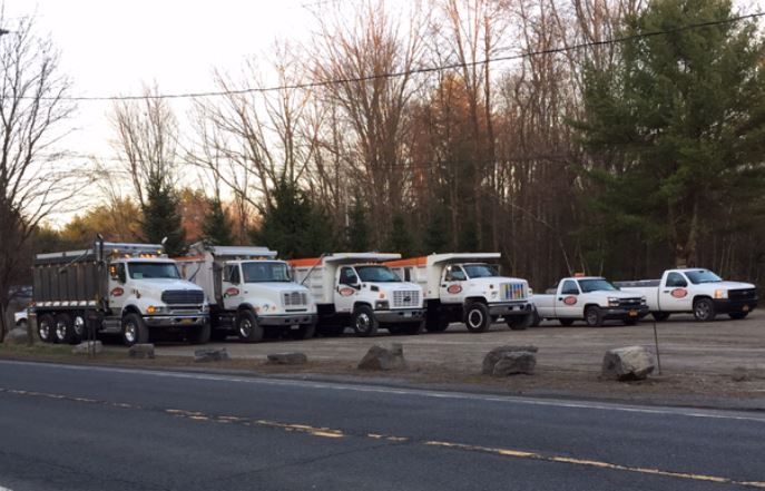 A row of dump trucks are parked on the side of the road.