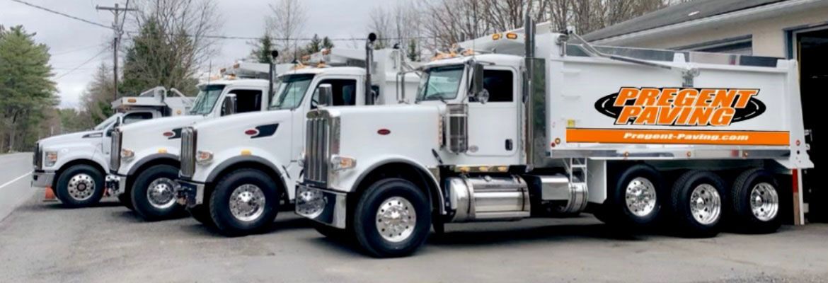 A row of dump trucks are parked next to each other on the side of the road.