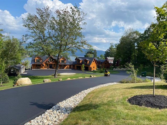 A large house is sitting on top of a hill next to a road.