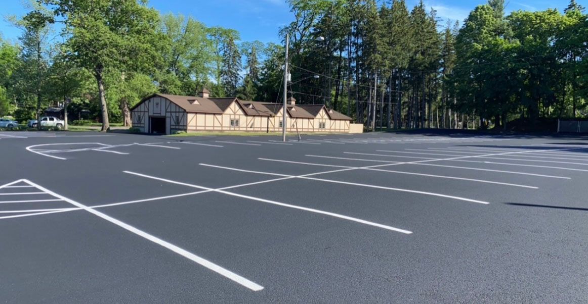A parking lot with a house in the background and trees in the background.