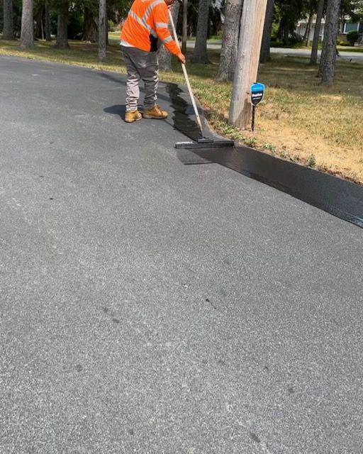 A man is painting a road with a broom