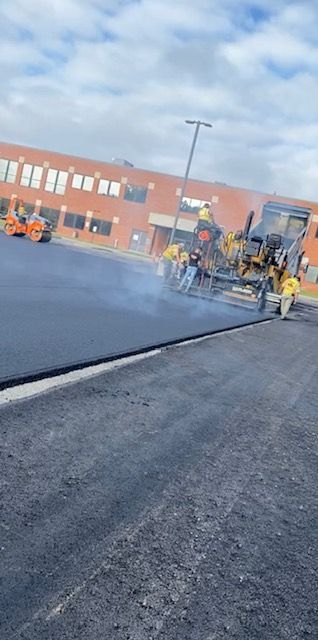A group of people are working on a road in front of a building.