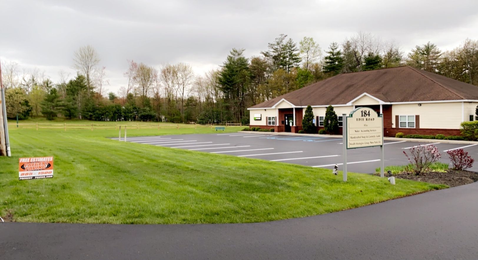 A large white building with a brown roof is sitting on top of a lush green field.