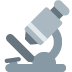 A grey icon of a compound light microscope.