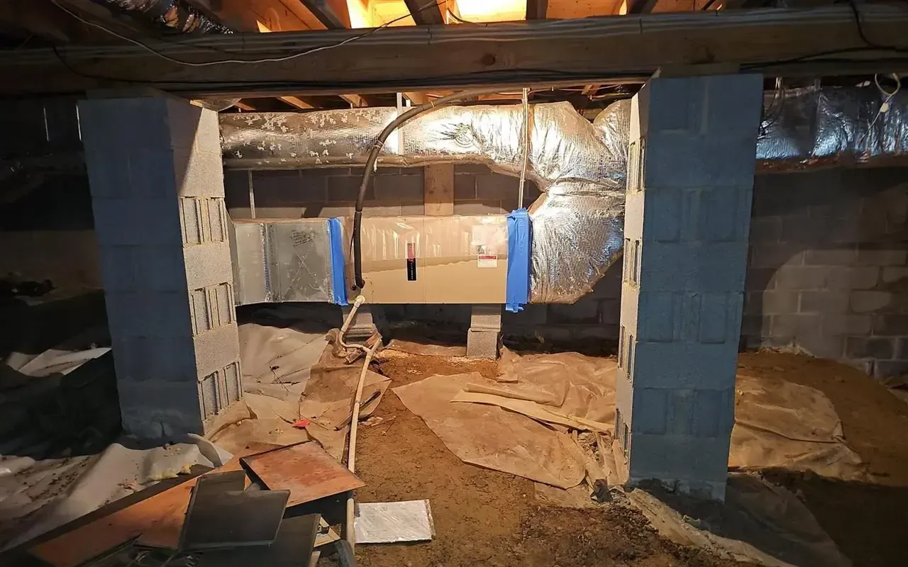 Crawl space featuring two cinder block support columns, HVAC metal ductwork, and loose debris on a dirt floor.