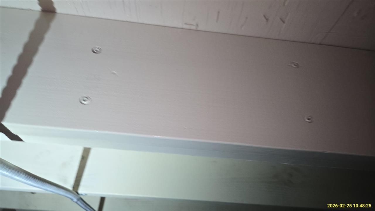 A close-up, high-angle view of a painted, light-colored wooden surface featuring four evenly spaced, recessed screws.