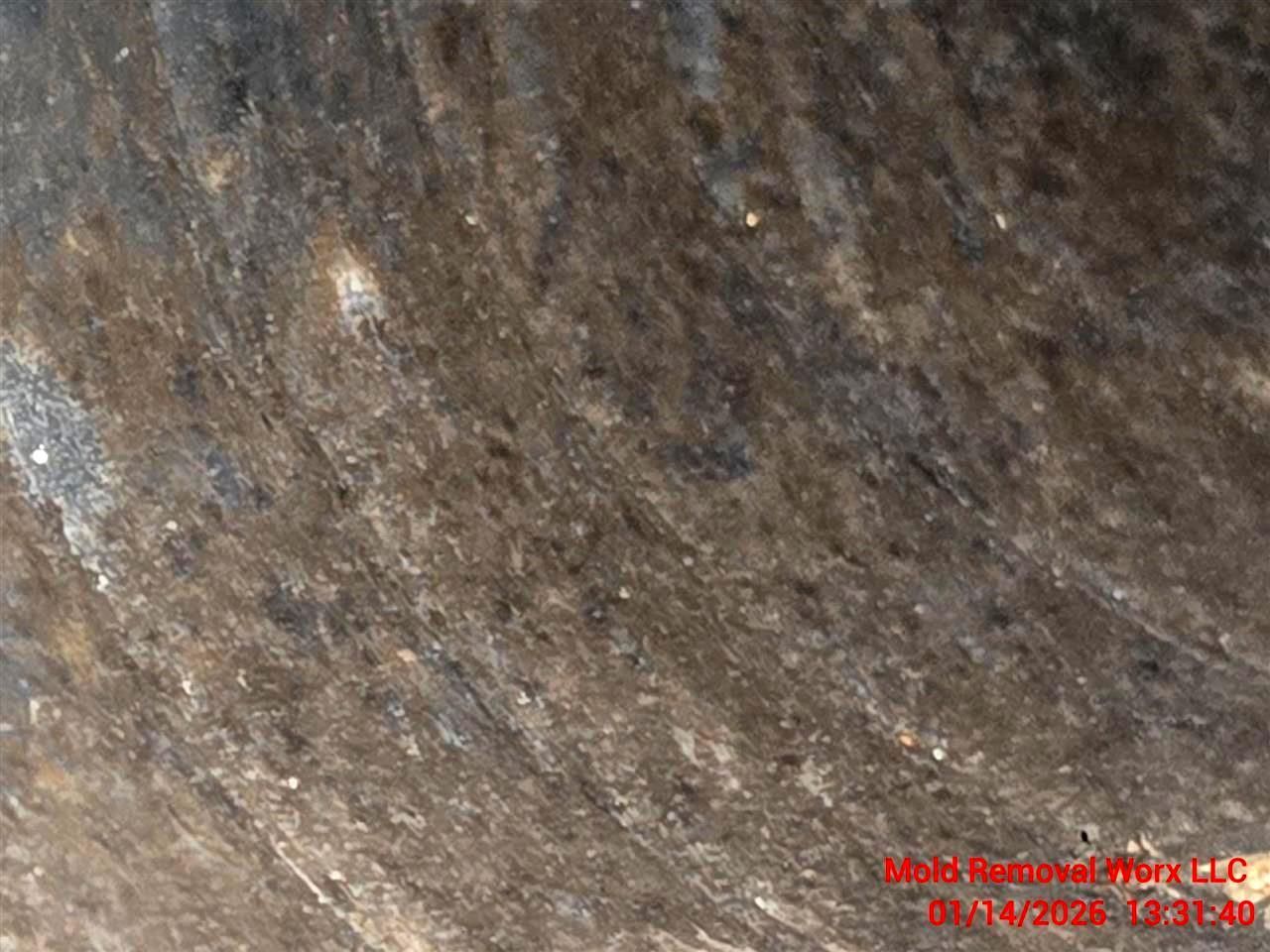 Close-up view of the rough, textured interior of a dark, weathered pipe with signs of wear and debris.