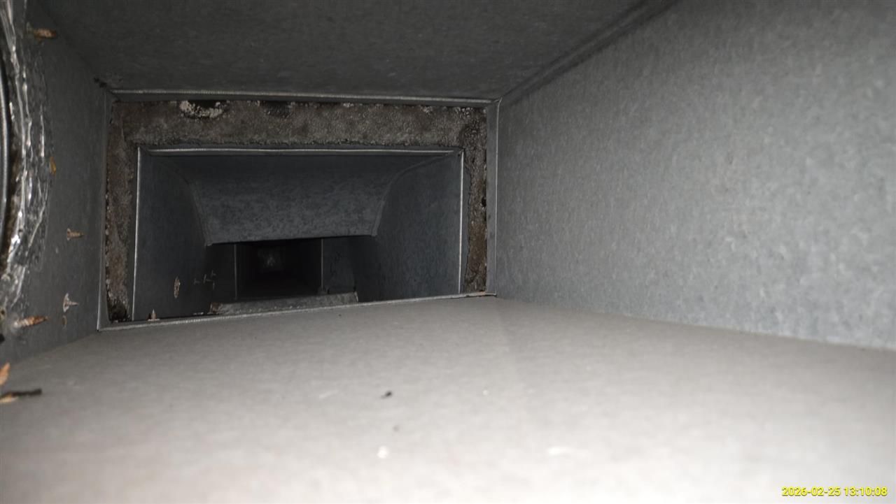 A view inside a rectangular metal air duct, showing the interior cavity, joint edges, and dark passage beyond.