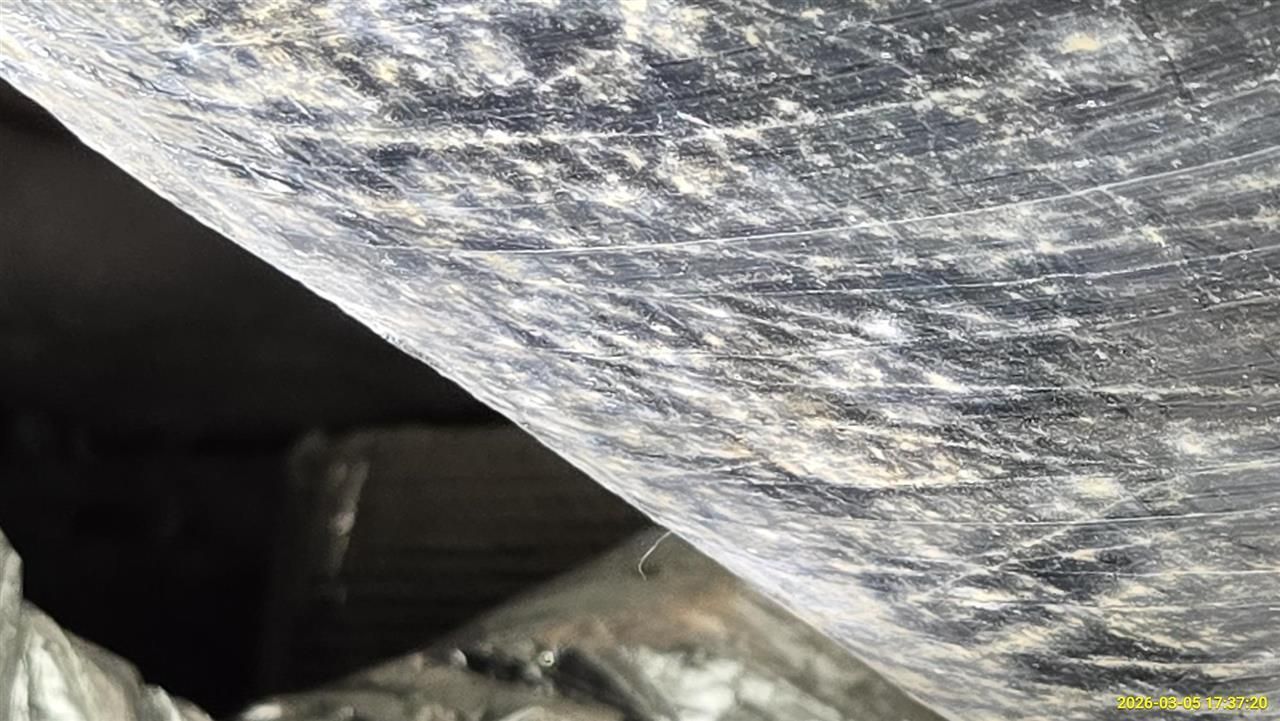 A close-up view of a dusty, dark, and textured surface with a sharp, angled edge against a blurred background.