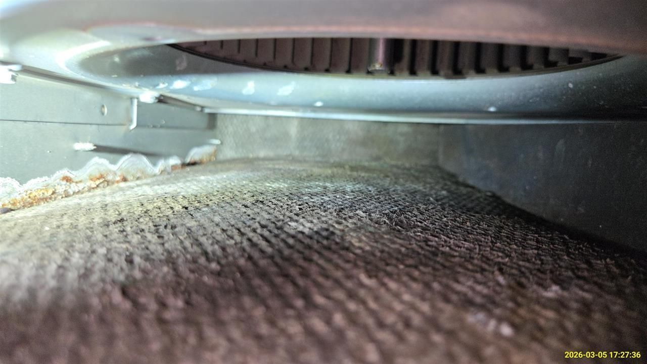 Close-up of a dirty, dark gray HVAC blower fan and the surrounding insulated internal air duct cavity.