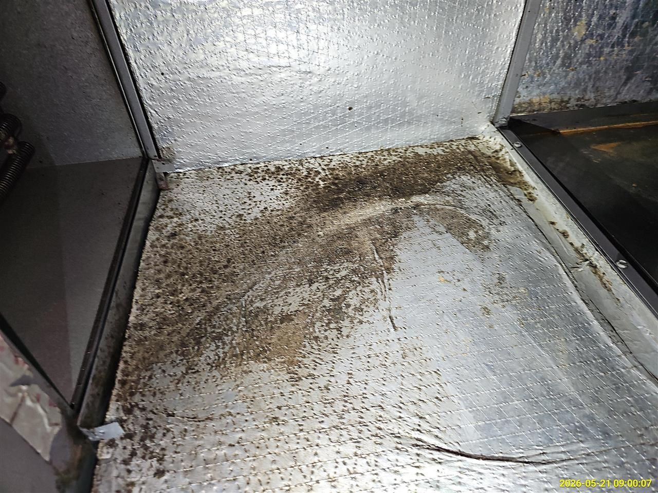 Dirty metal floor with scattered debris and grime inside an industrial container or chute