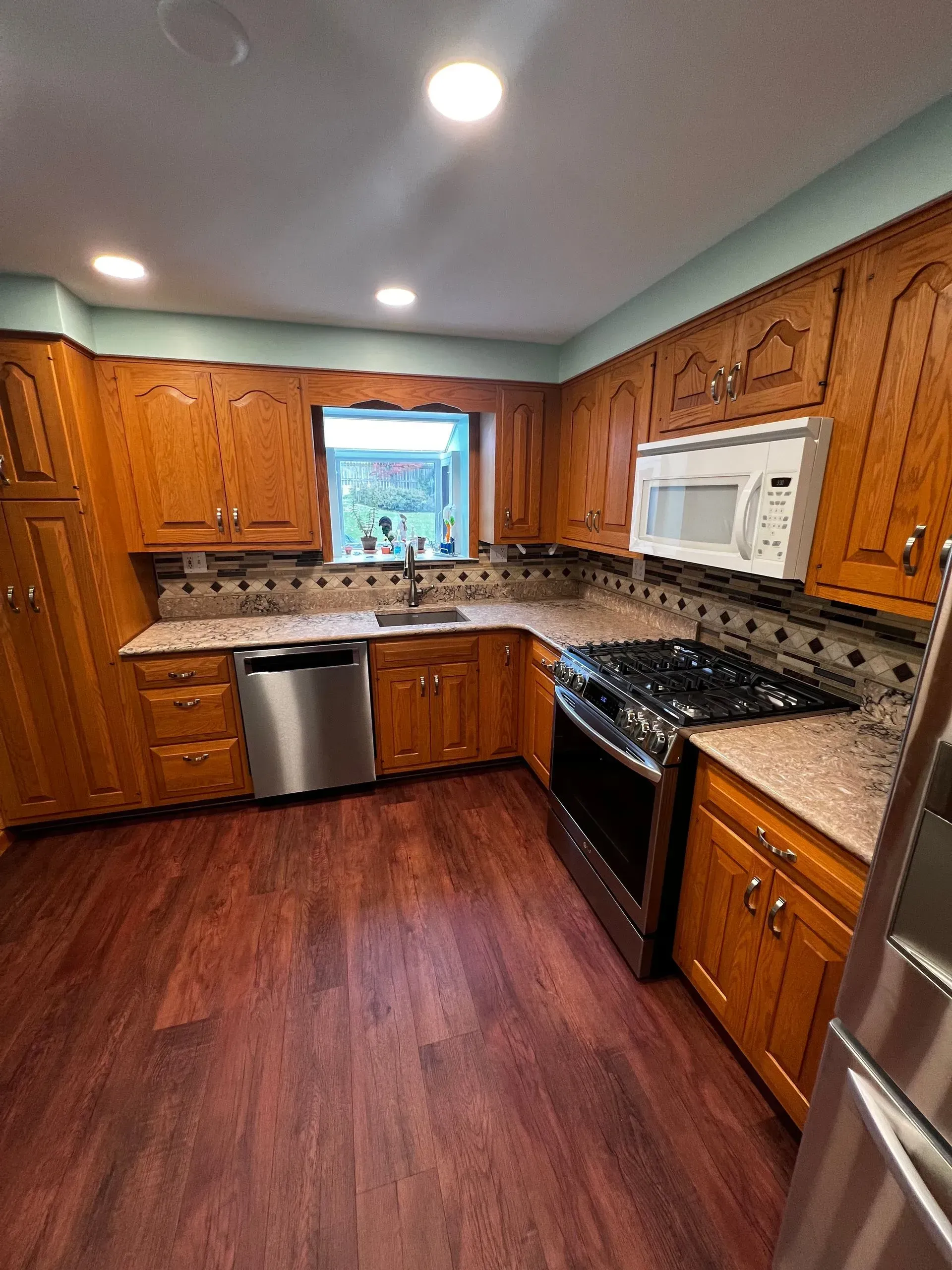 A kitchen with wooden cabinets, stainless steel appliances, and dark flooring.