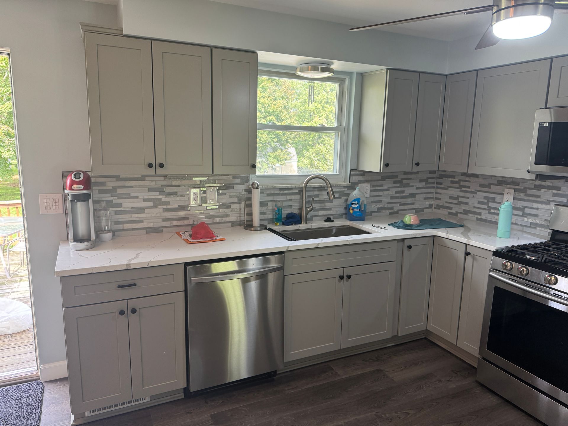 Gray kitchen with white countertops, stainless steel appliances, and a tiled backsplash.