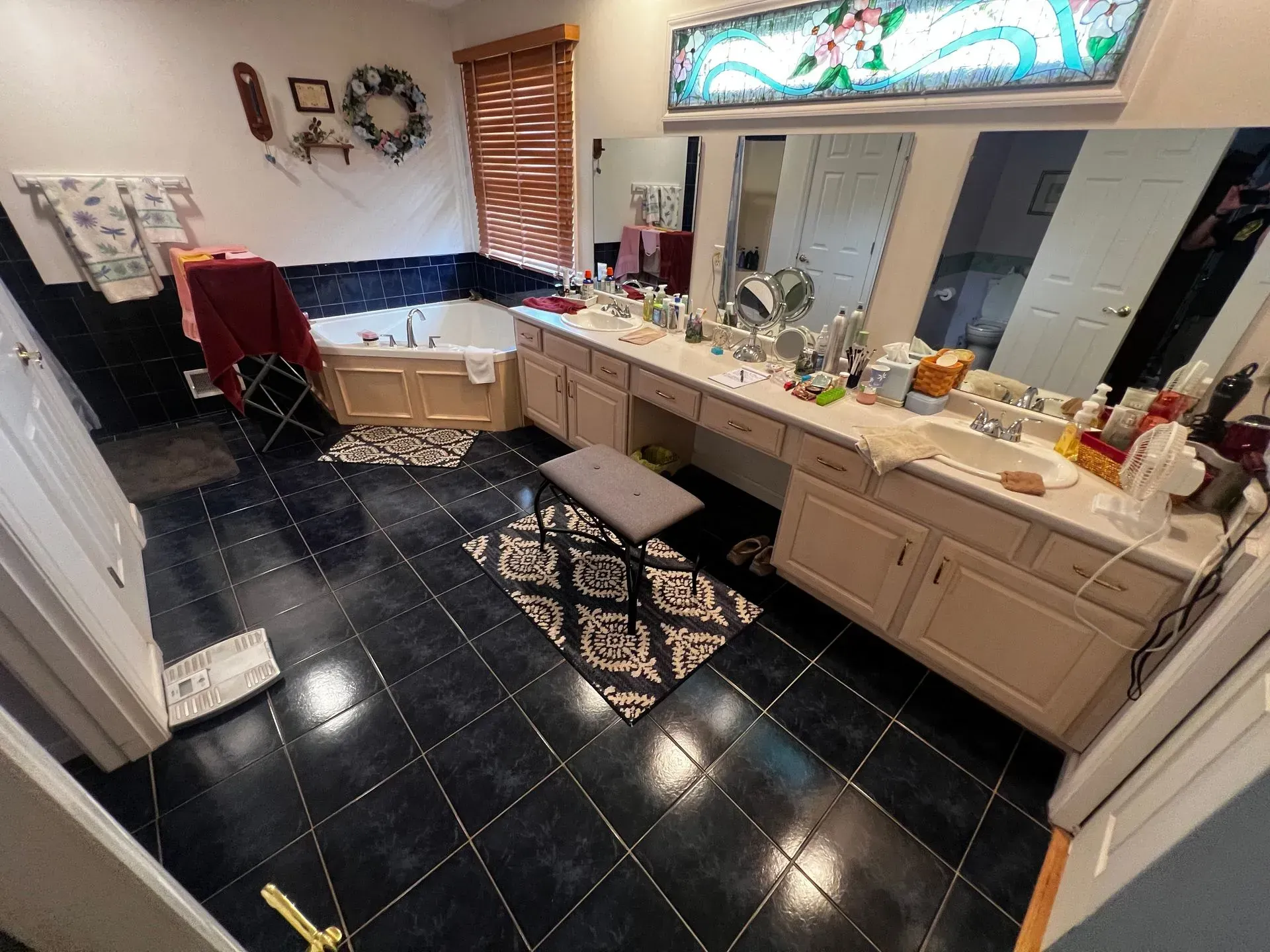Bathroom with black tiled floor, vanity with multiple mirrors, and a jacuzzi tub.