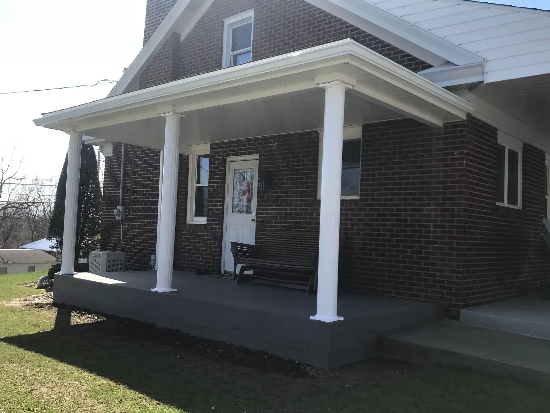 Brick house with a covered porch supported by white columns.