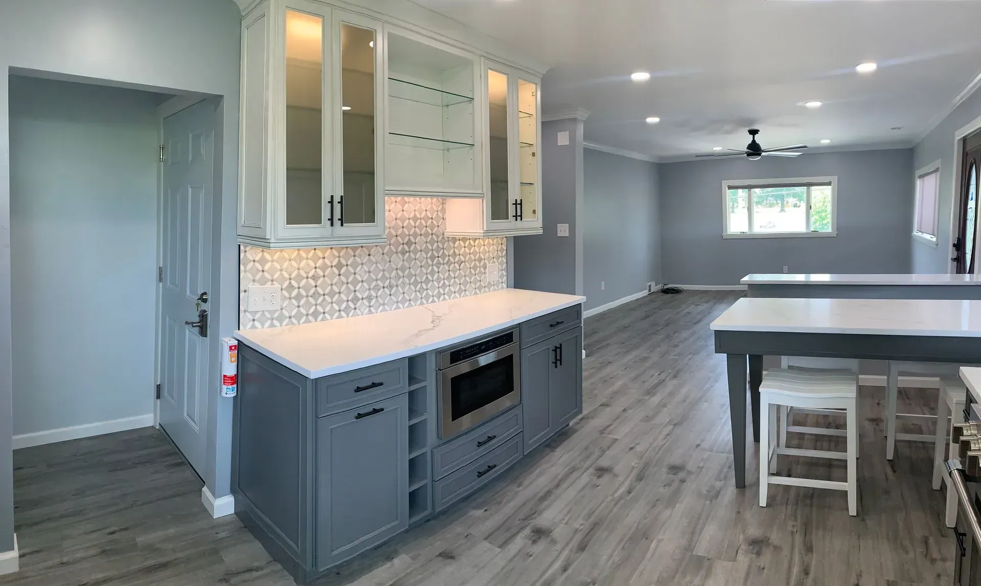 Modern kitchen with gray cabinets, white countertops, and open floor plan.