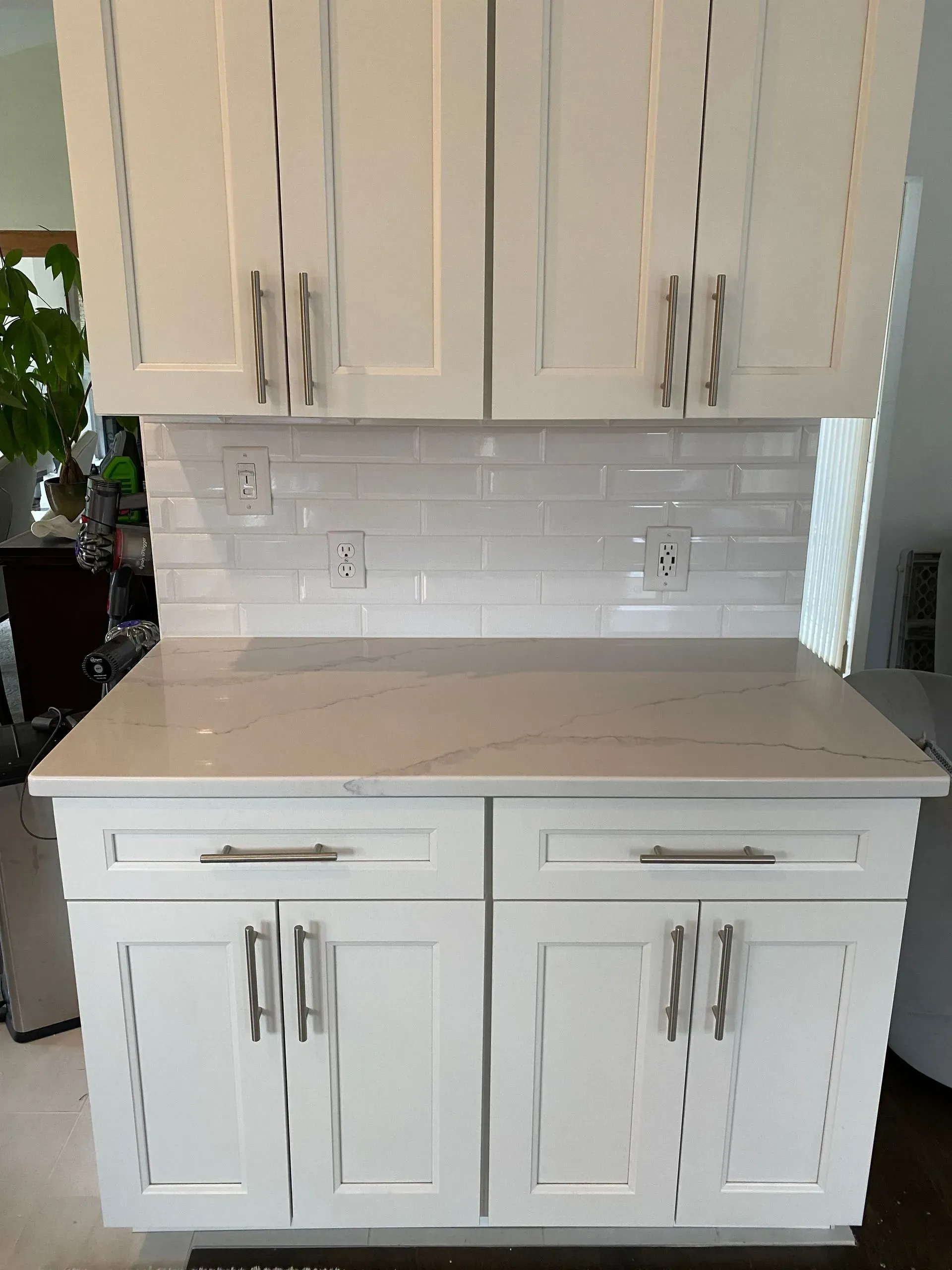 White kitchen cabinets with light countertops and white tile backsplash.