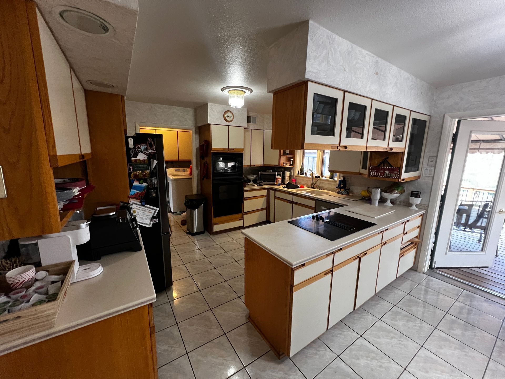 Kitchen with light cabinets, tile floor, and a black cooktop on the island.