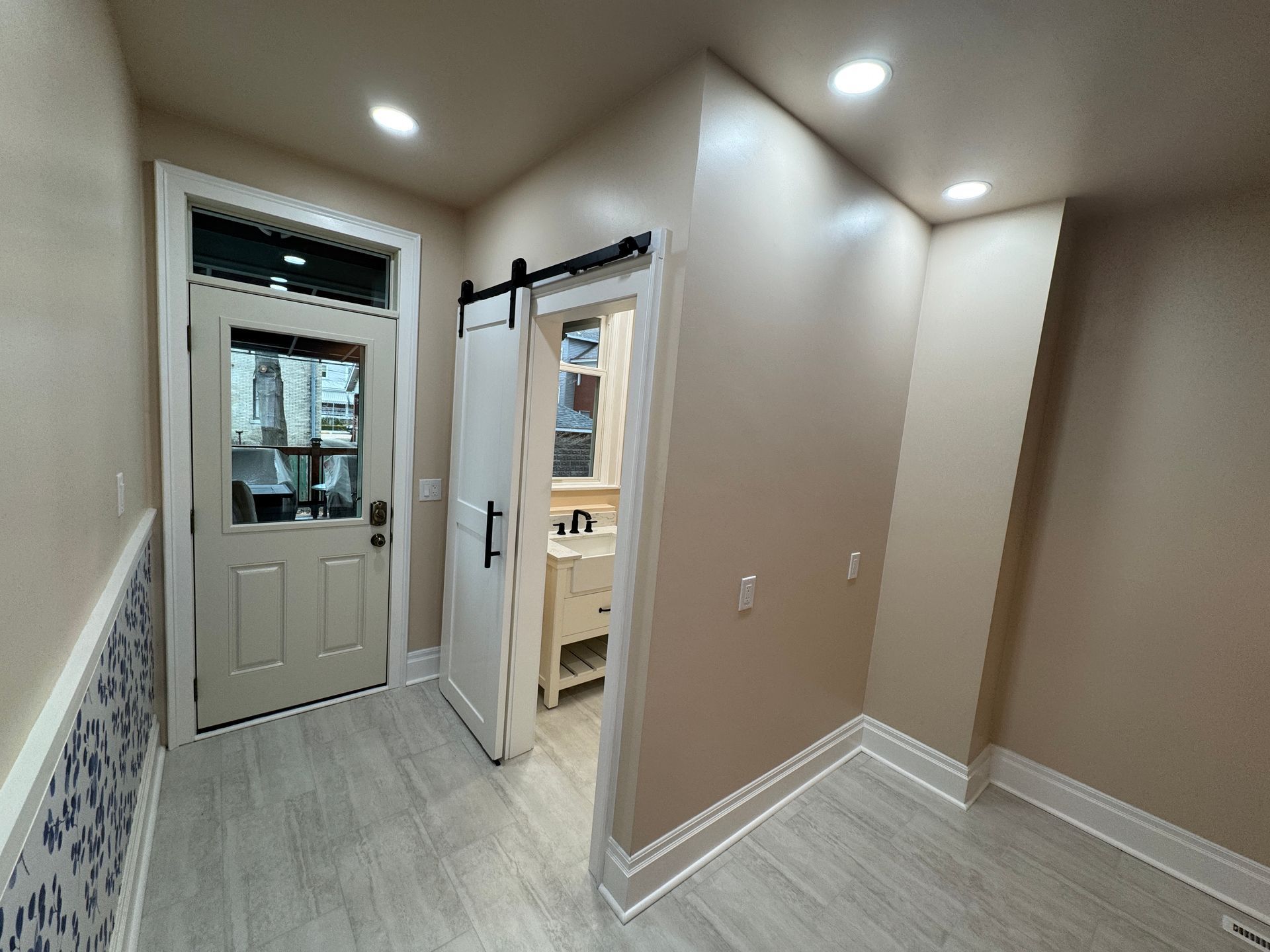 Interior hallway with a door, barn door, and a partially visible bathroom.