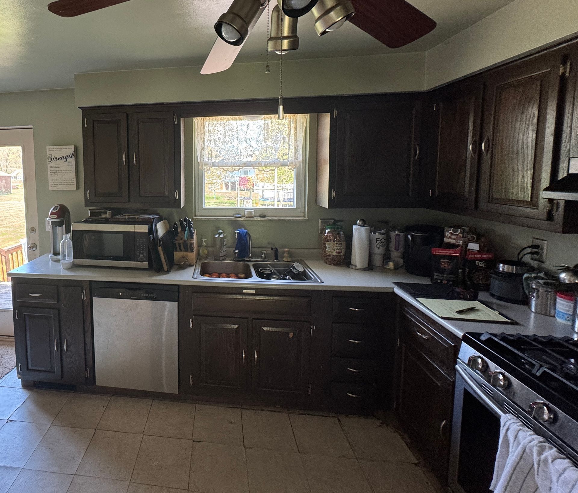 Kitchen with dark brown cabinets, a window above the sink, and a stainless steel dishwasher and stove.
