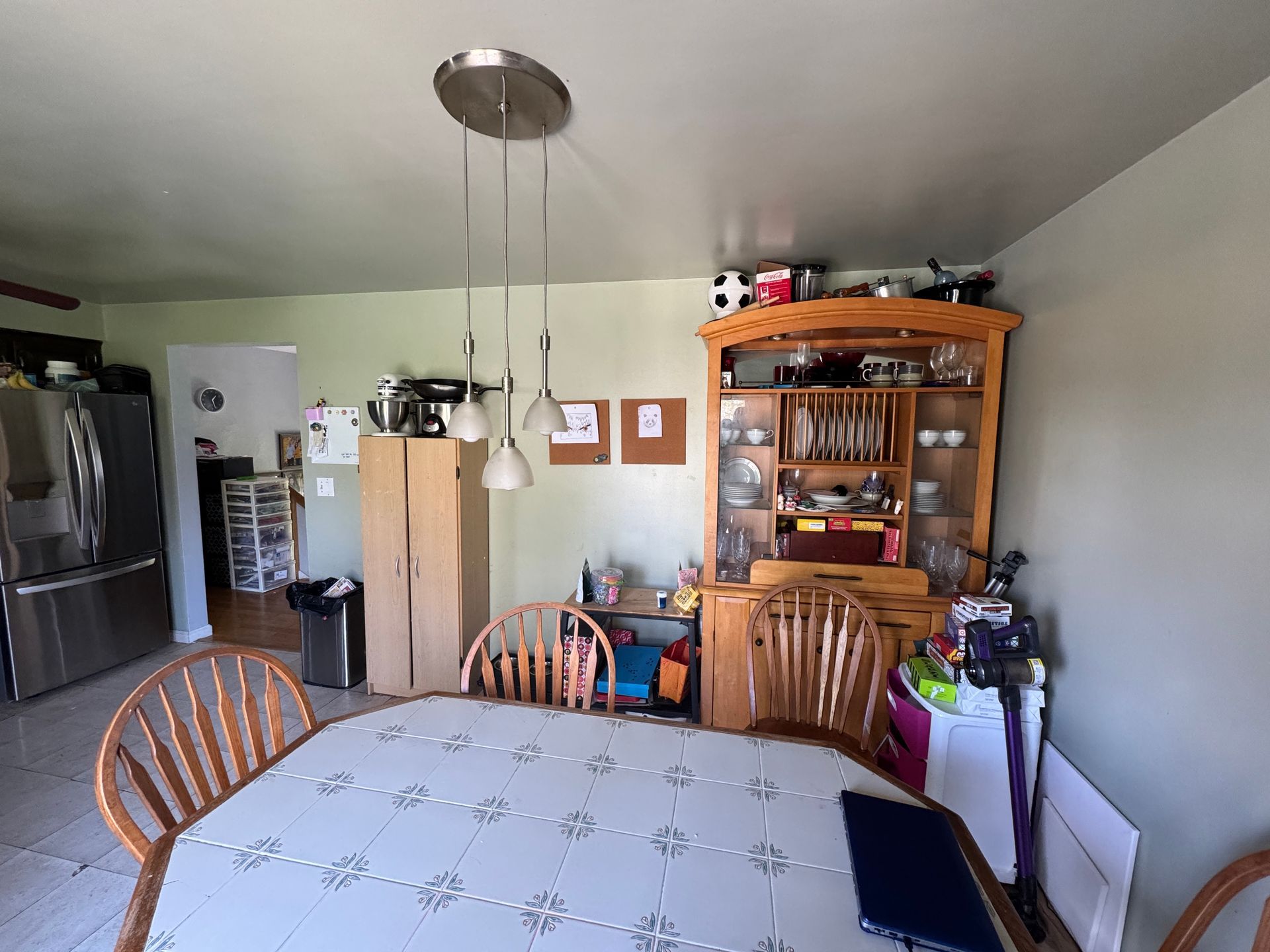 Dining room with a table, chairs, hutch, refrigerator, and light fixture.