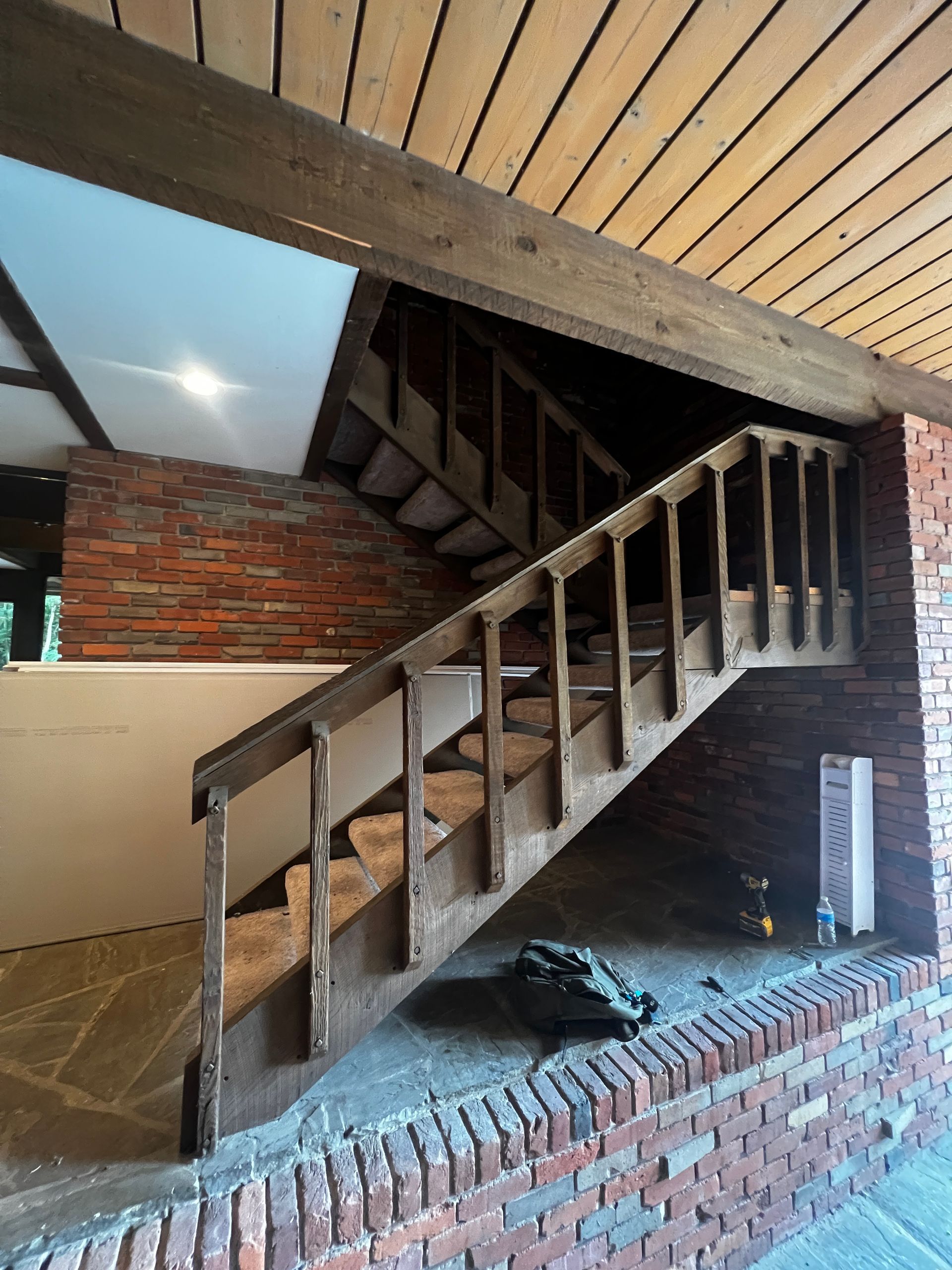 Wooden staircase with brick wall and ceiling.