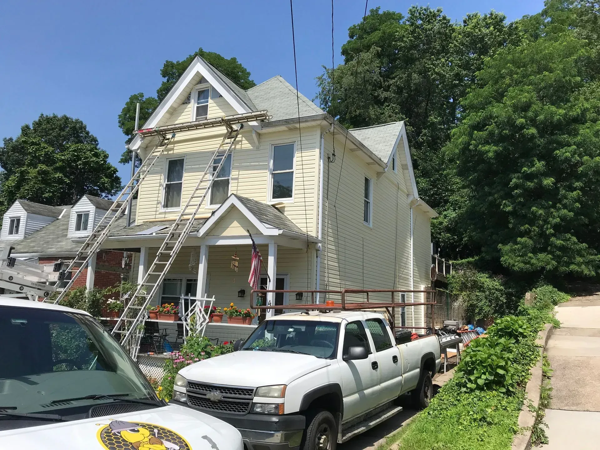 House with ladders, truck, and construction materials on a sunny day.