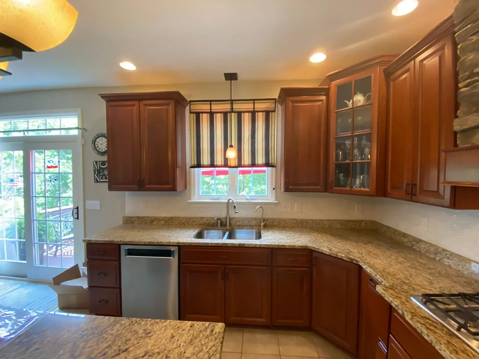 Kitchen with brown cabinets, granite countertops, and striped window shade.