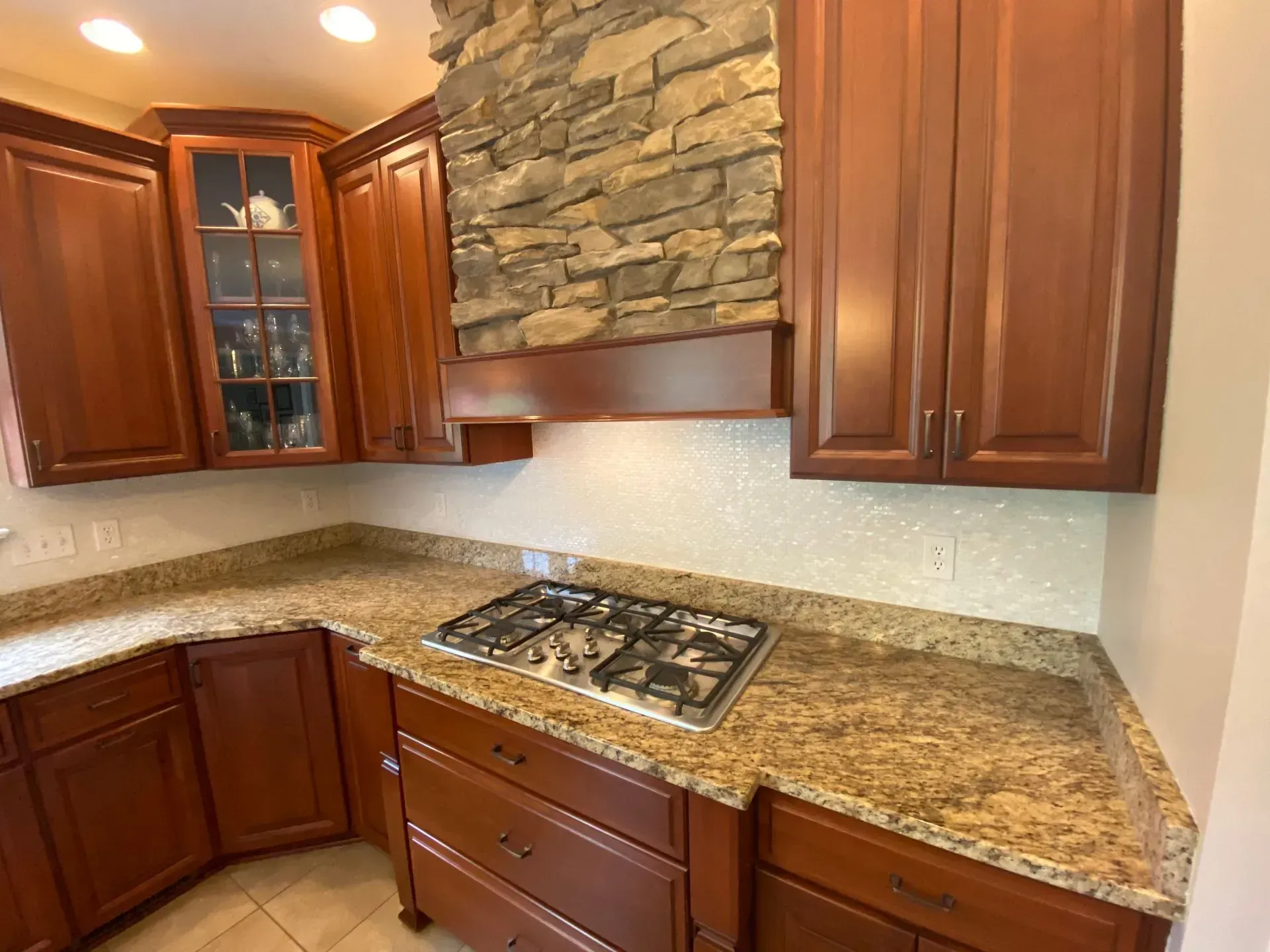 Kitchen with dark wood cabinets, granite countertops, and stone range hood.