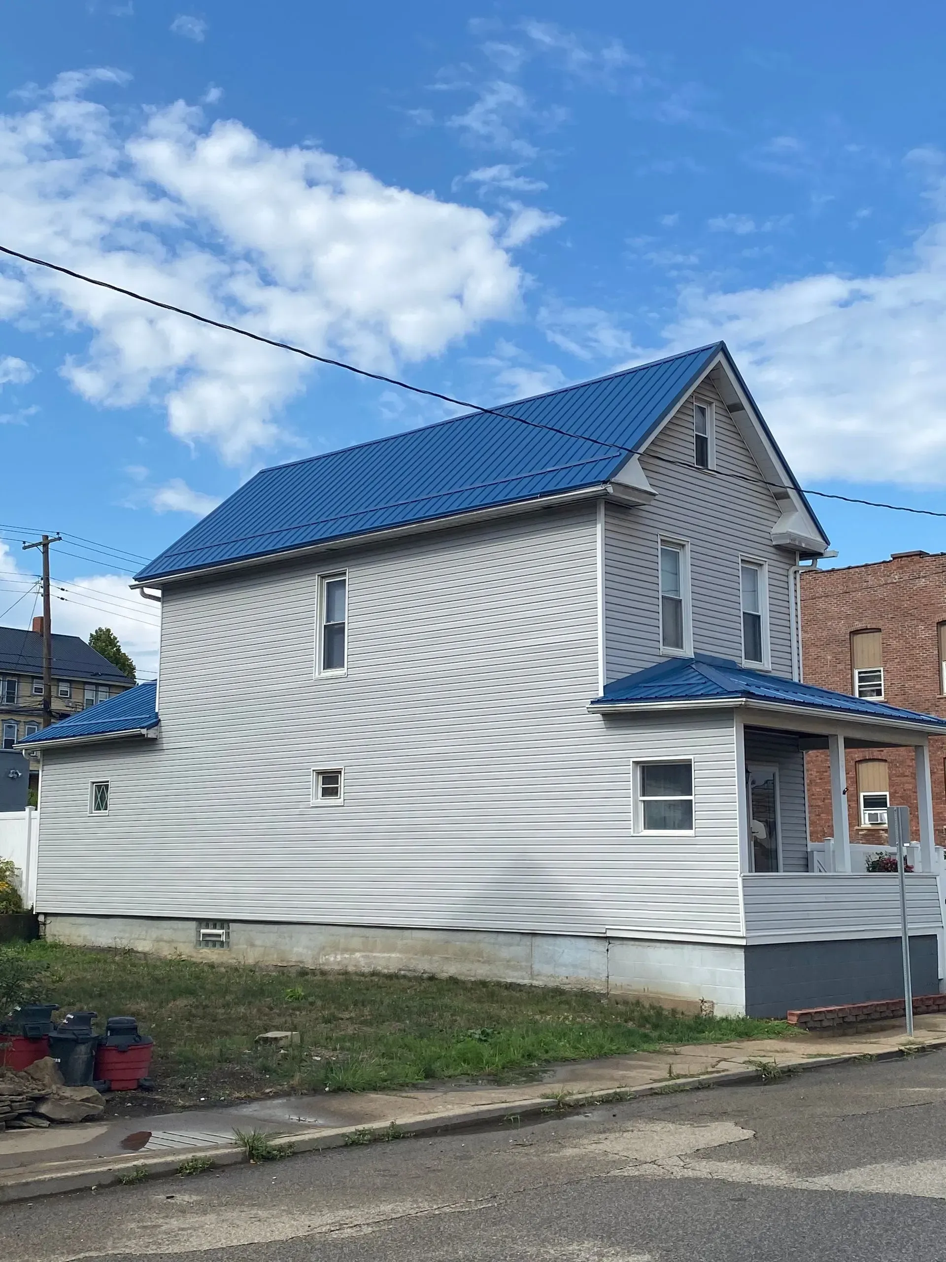House with blue roof and white siding against a blue sky.