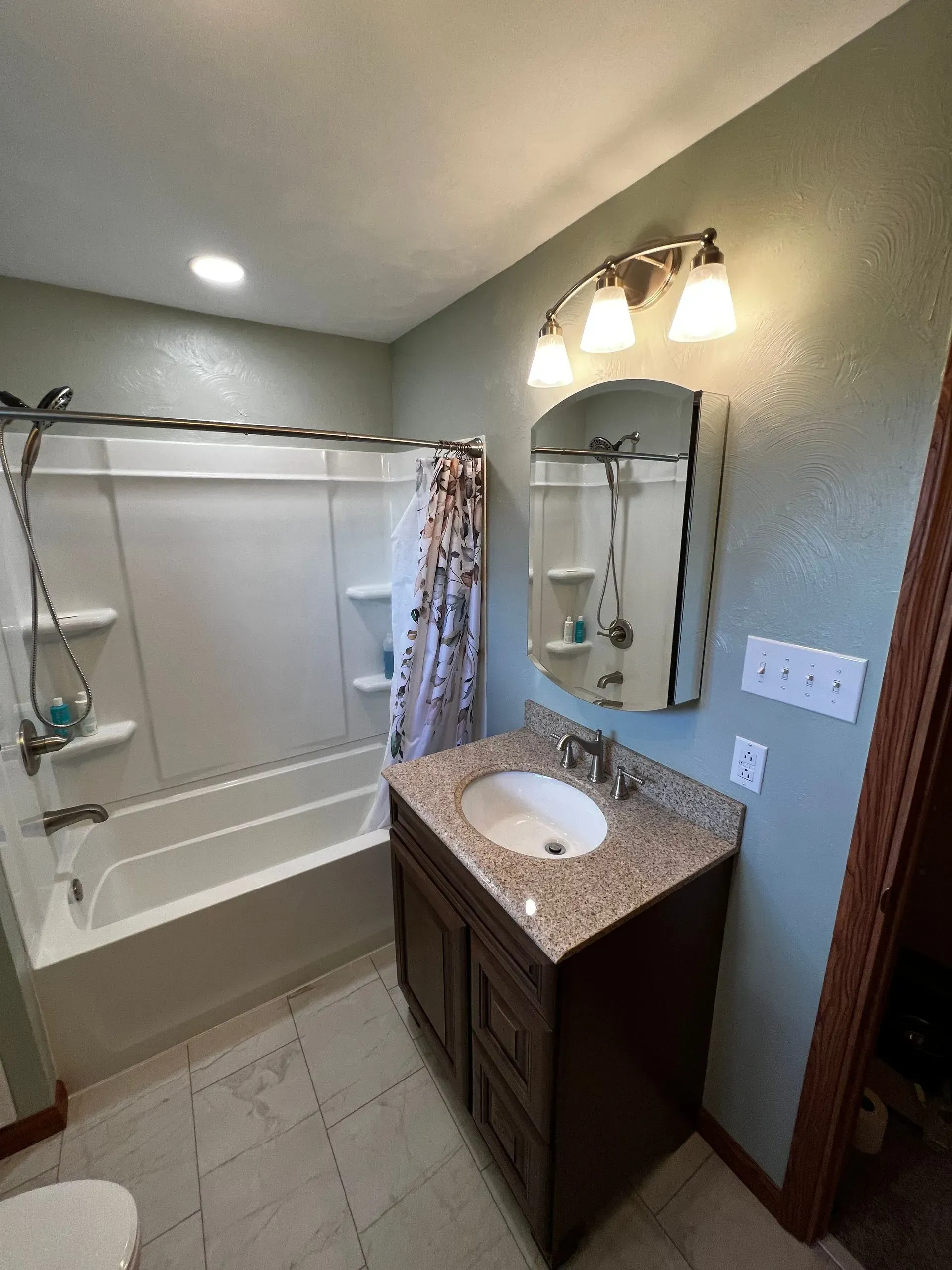 Bathroom with a white tub, brown vanity, and green walls.