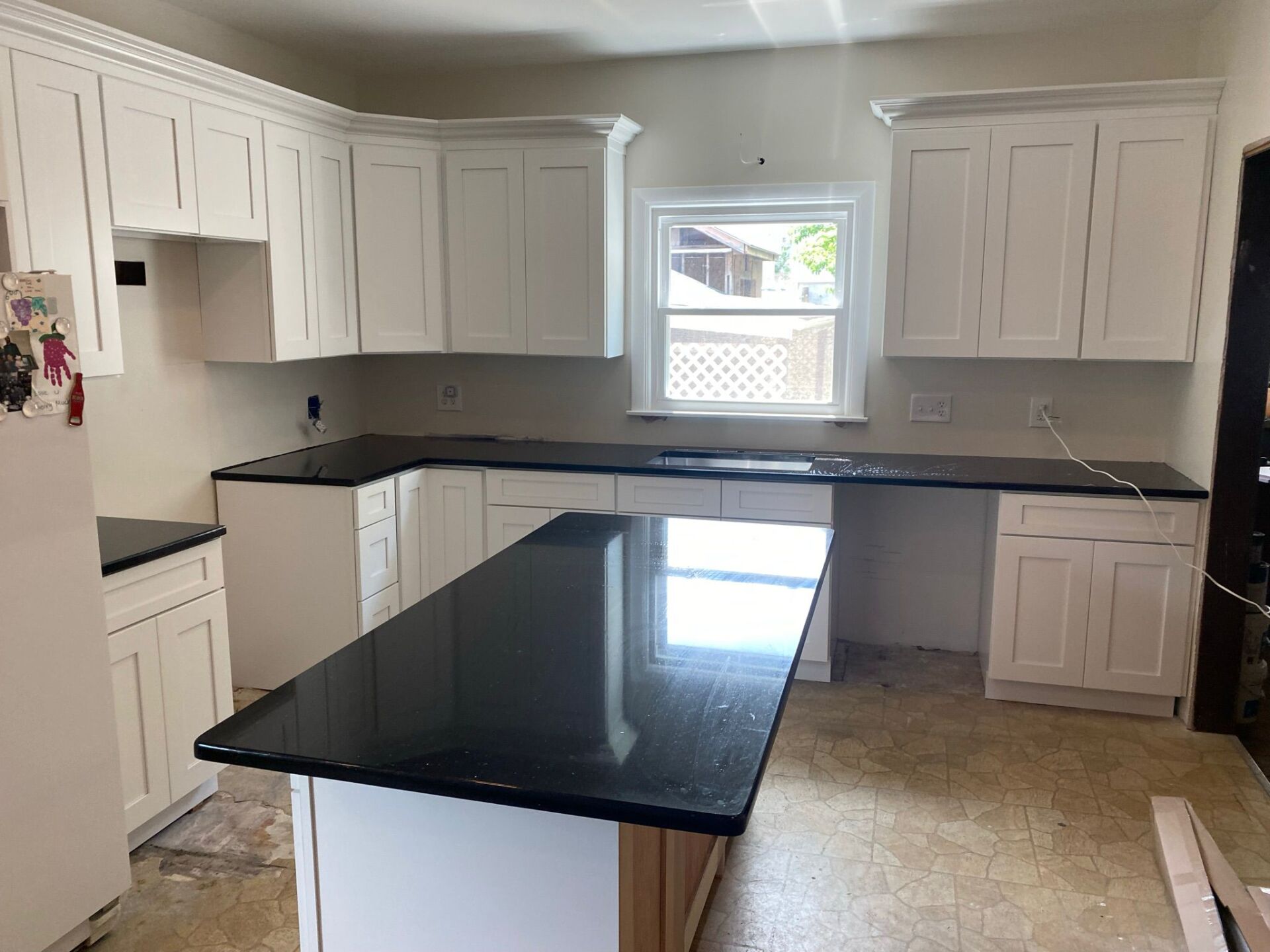 A kitchen with white cabinets and black granite counter tops.
