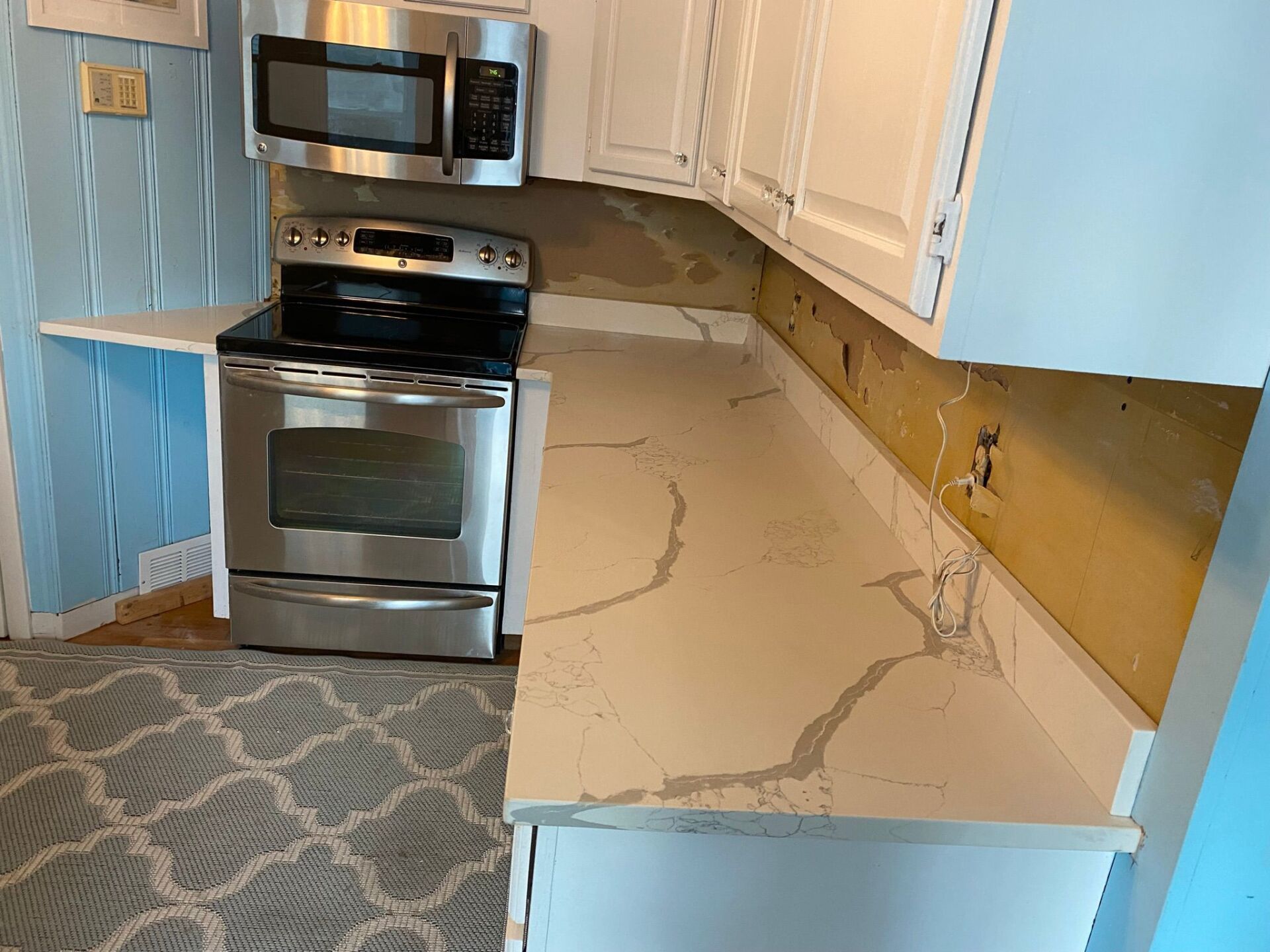 A kitchen with a stove , microwave , and counter tops.