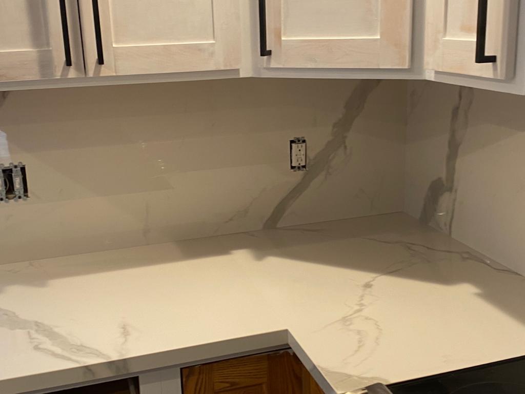 A kitchen with white cabinets and a white counter top.
