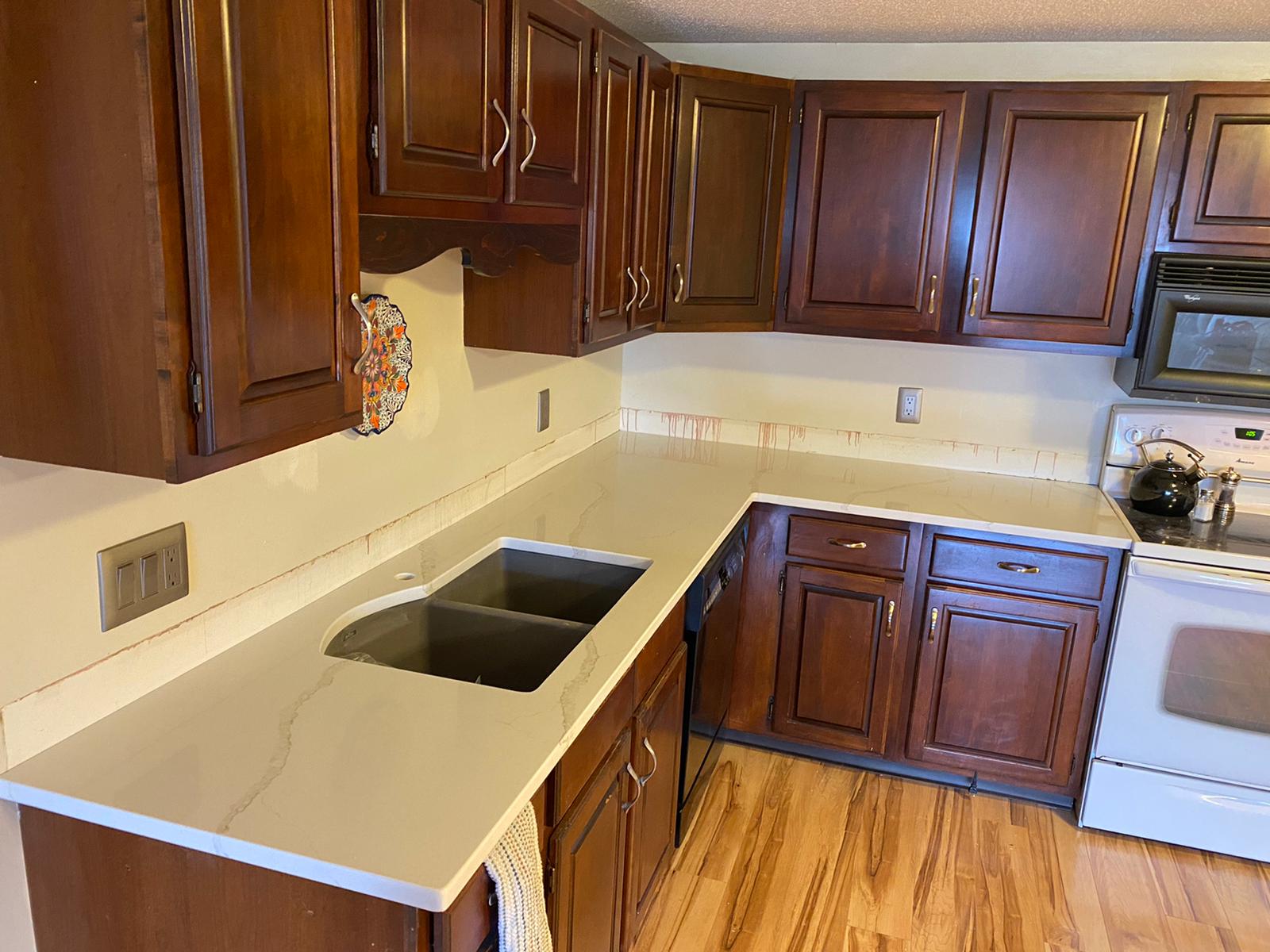 A kitchen with wooden cabinets , a sink , stove and microwave.