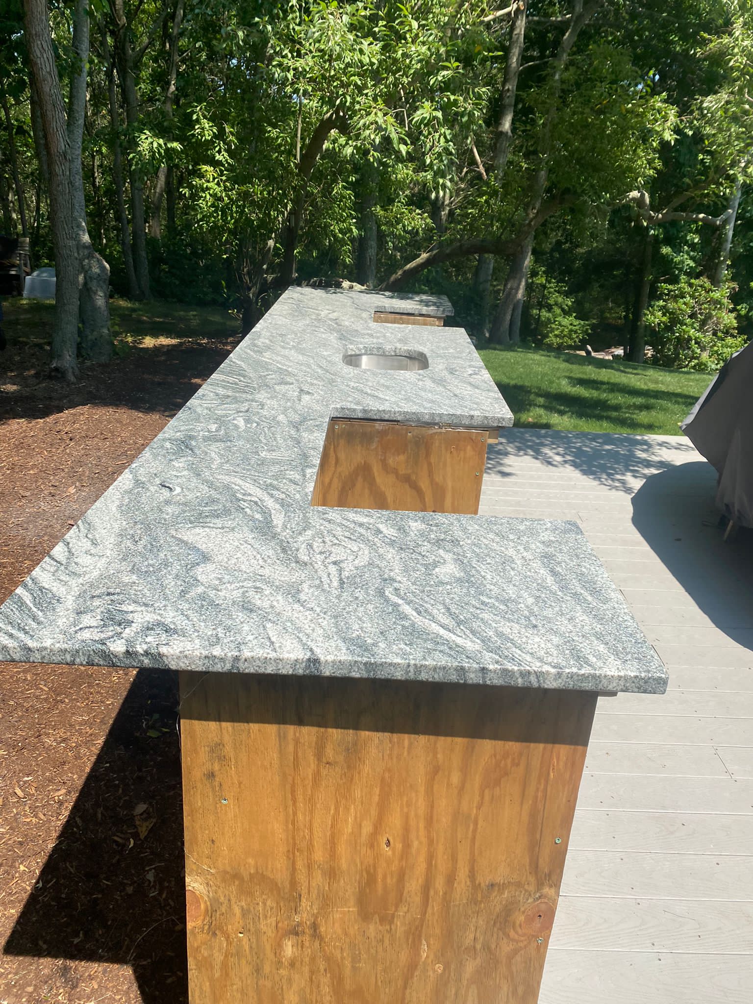 A long granite counter top is sitting on top of a wooden table.