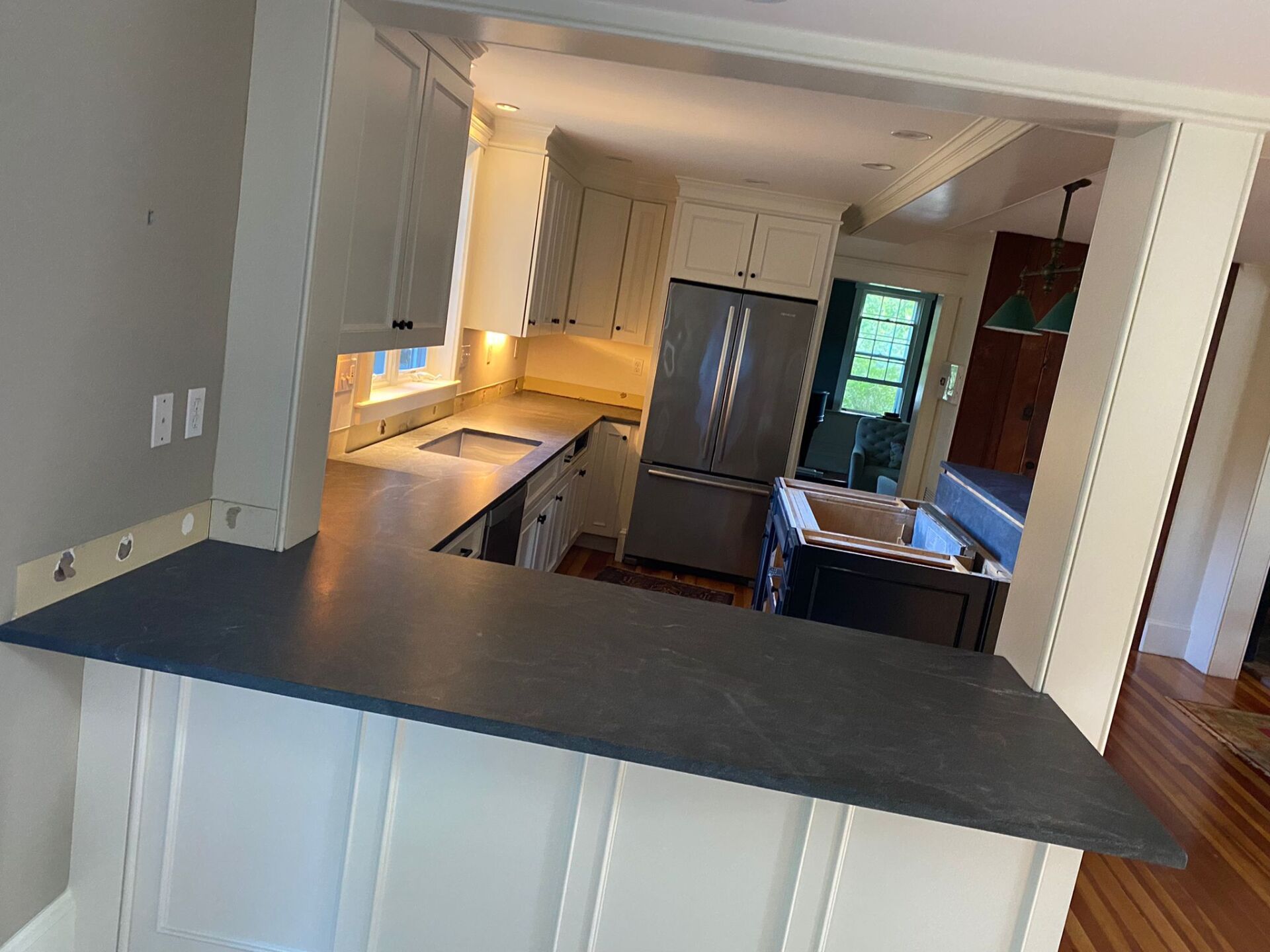 A kitchen with white cabinets and a black counter top.