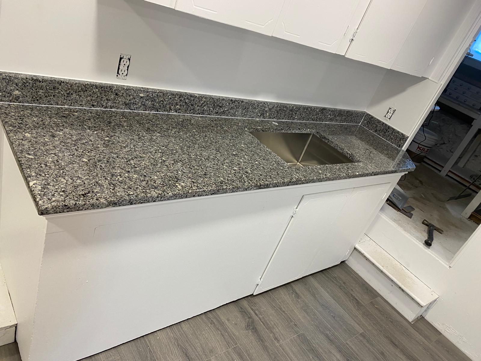 A kitchen with granite counter tops and a stainless steel sink.