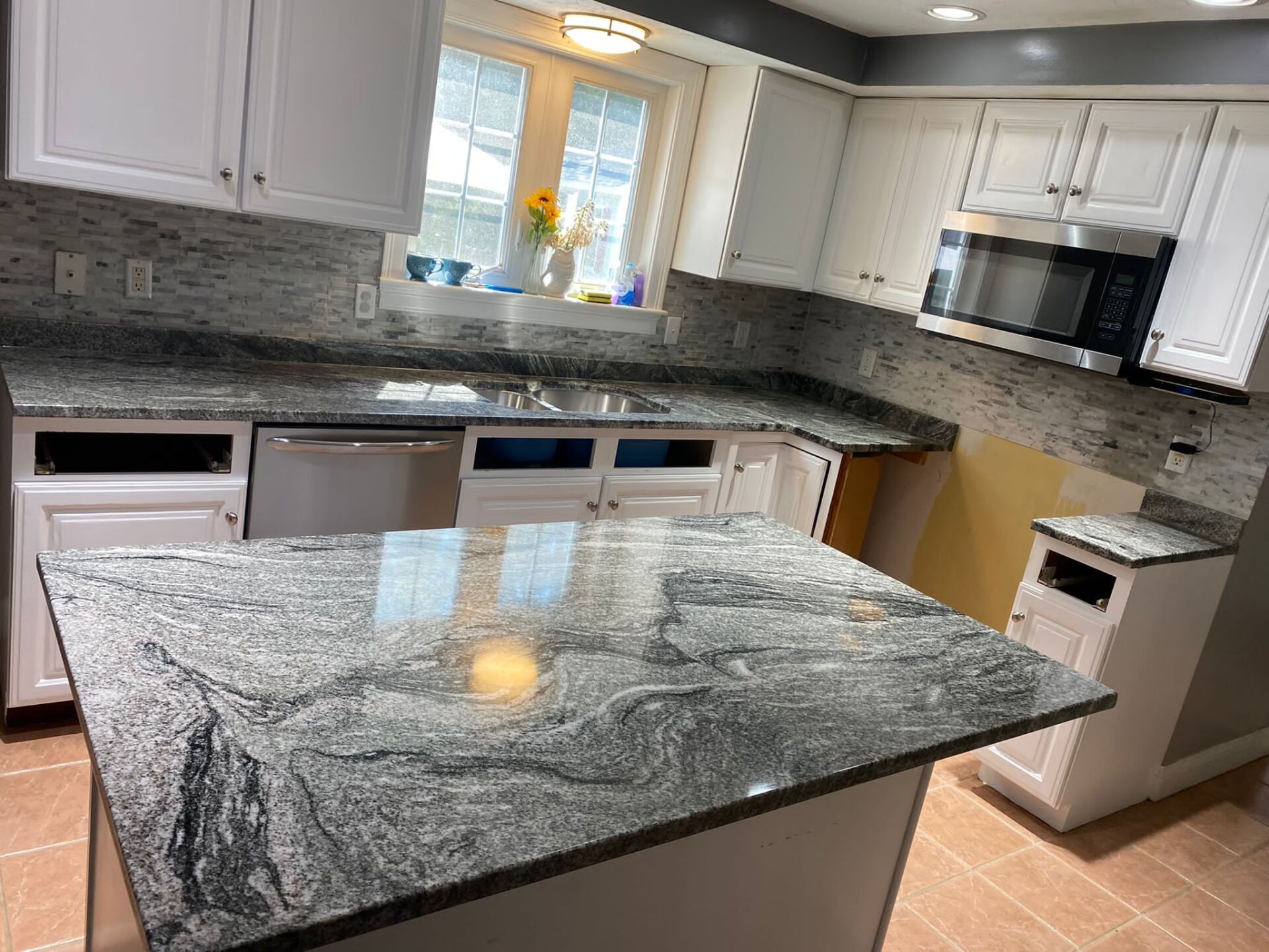 A kitchen with granite counter tops and white cabinets.