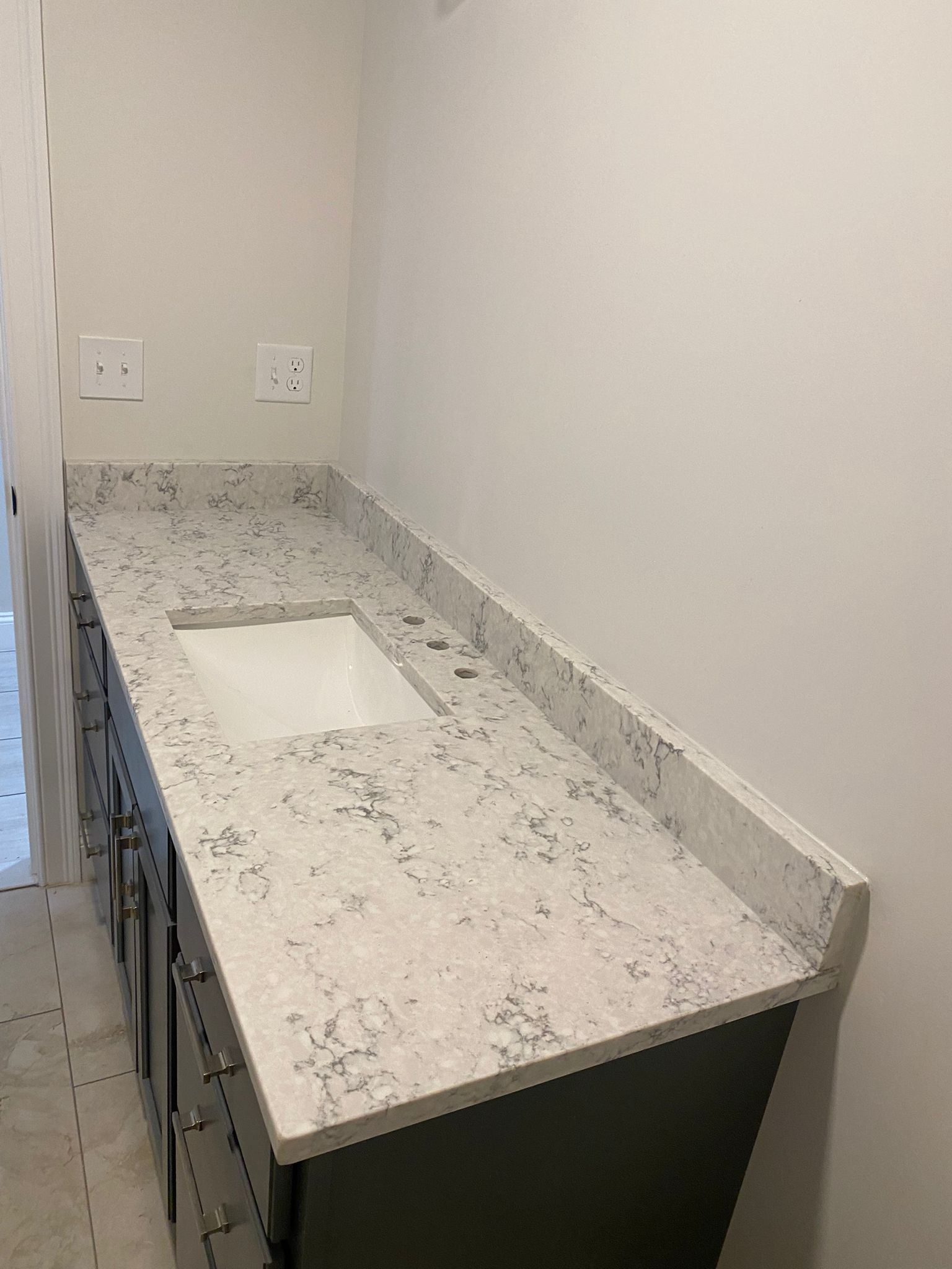 A bathroom vanity with a sink and a granite counter top.