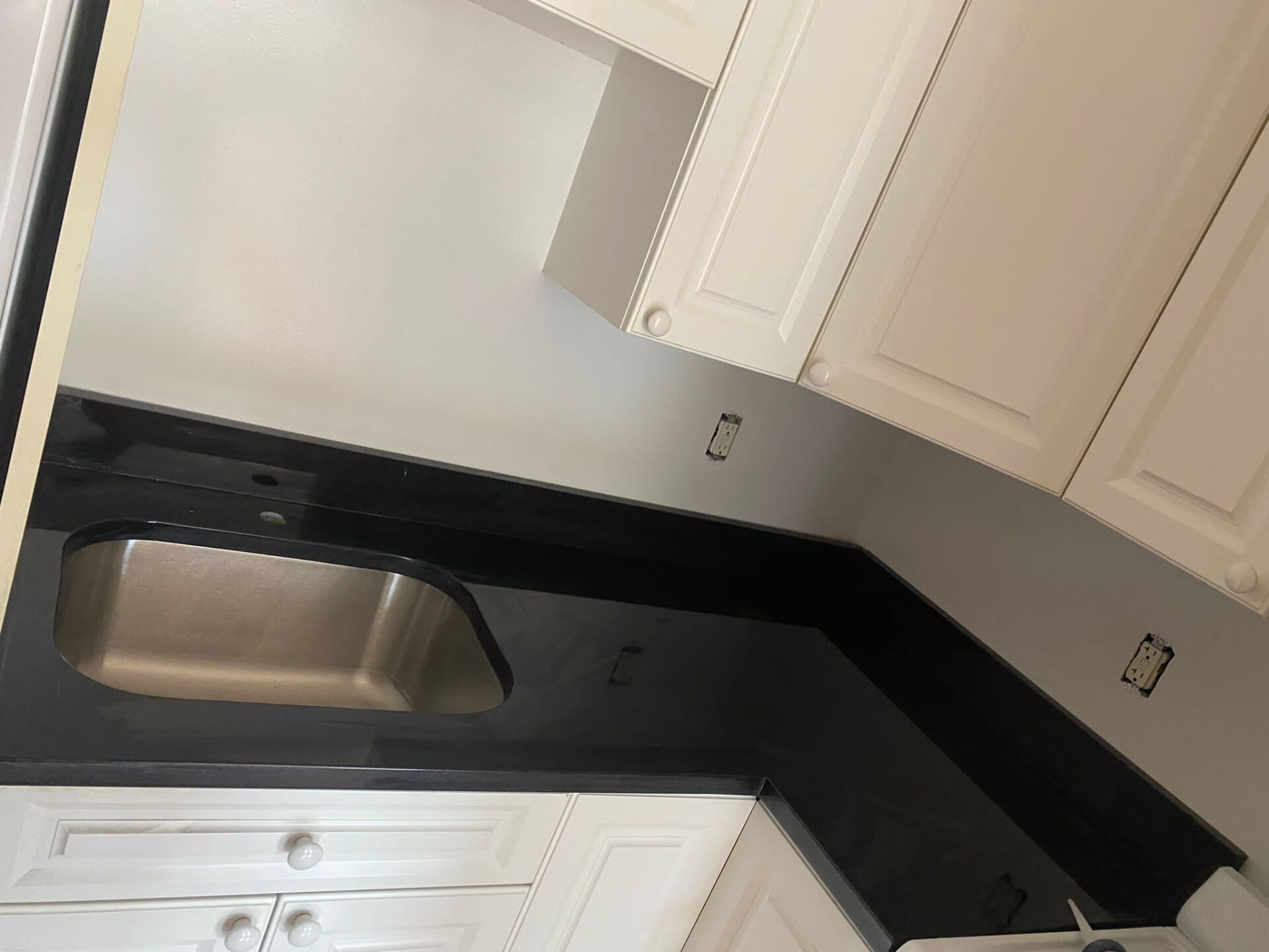 A kitchen with white cabinets and a stainless steel sink