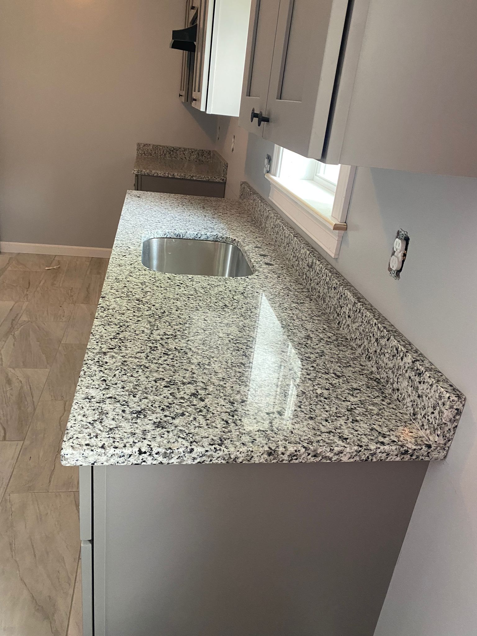 A kitchen with granite counter tops and a stainless steel sink.