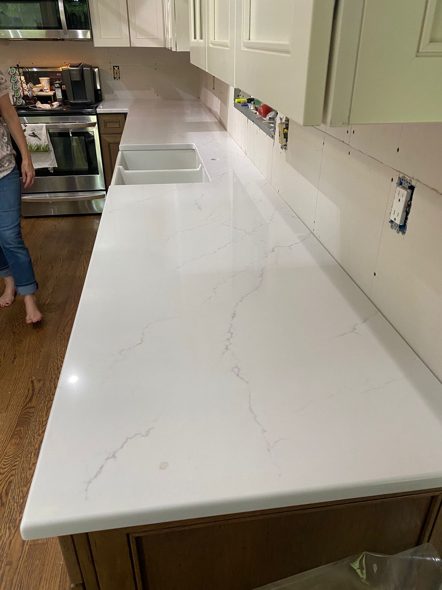 A woman is standing in a kitchen with a large white counter top.