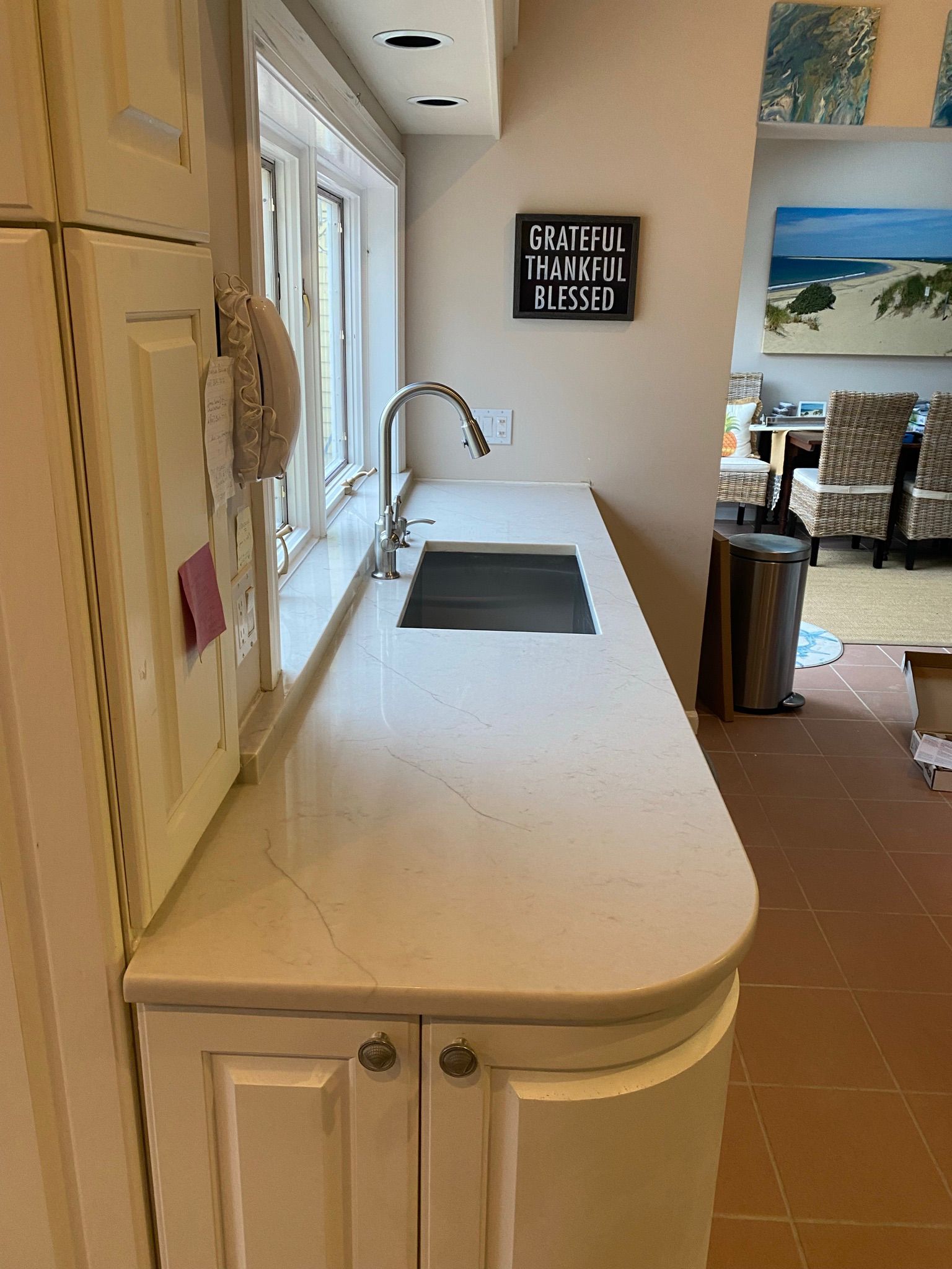 A kitchen with white cabinets , a sink and a window.