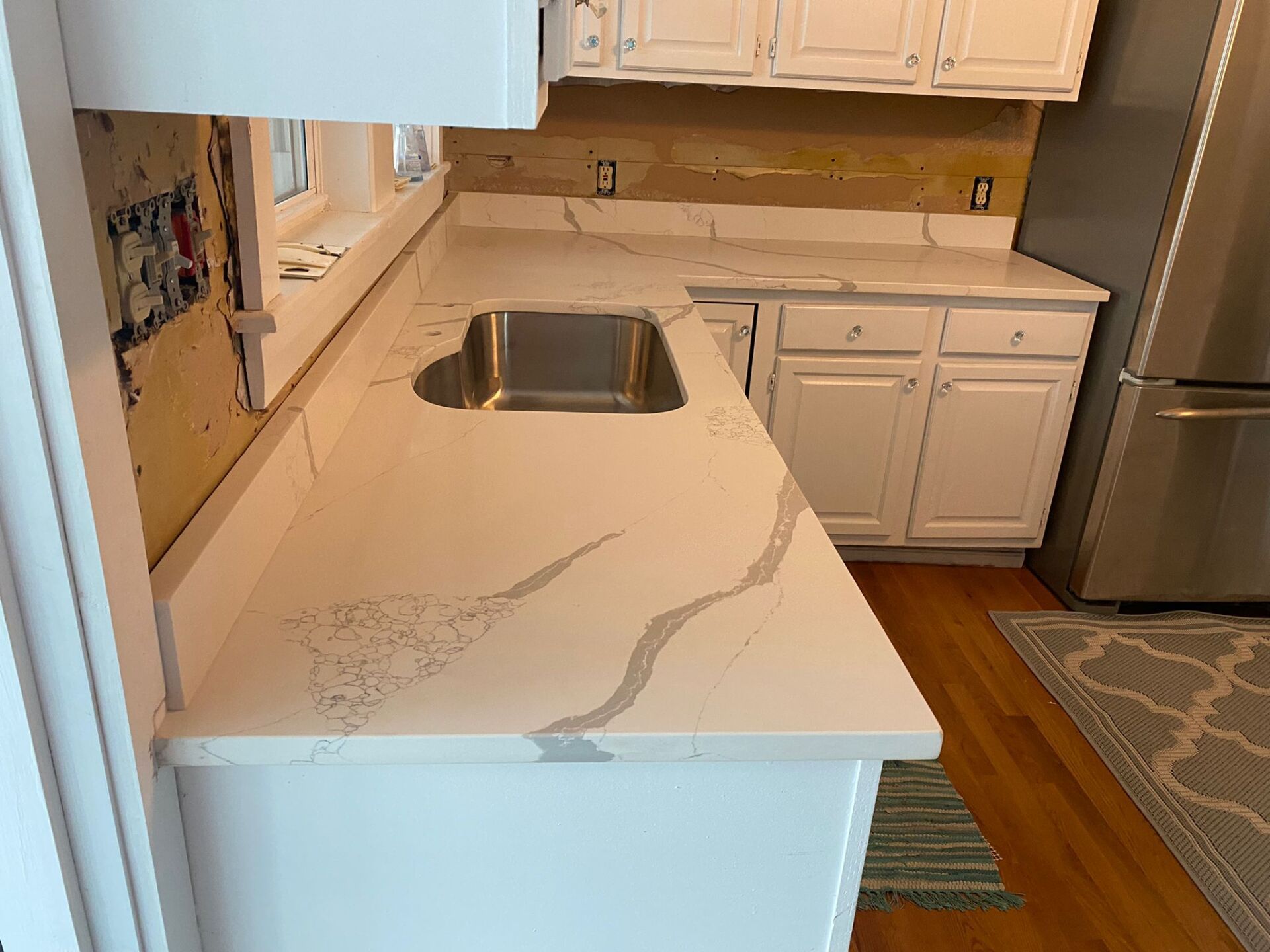 A kitchen with white cabinets and a stainless steel sink.