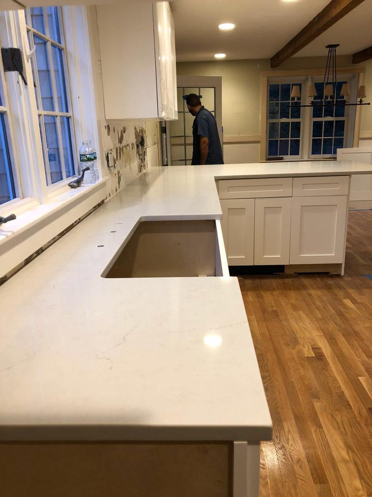 A man is standing in a kitchen next to a sink.