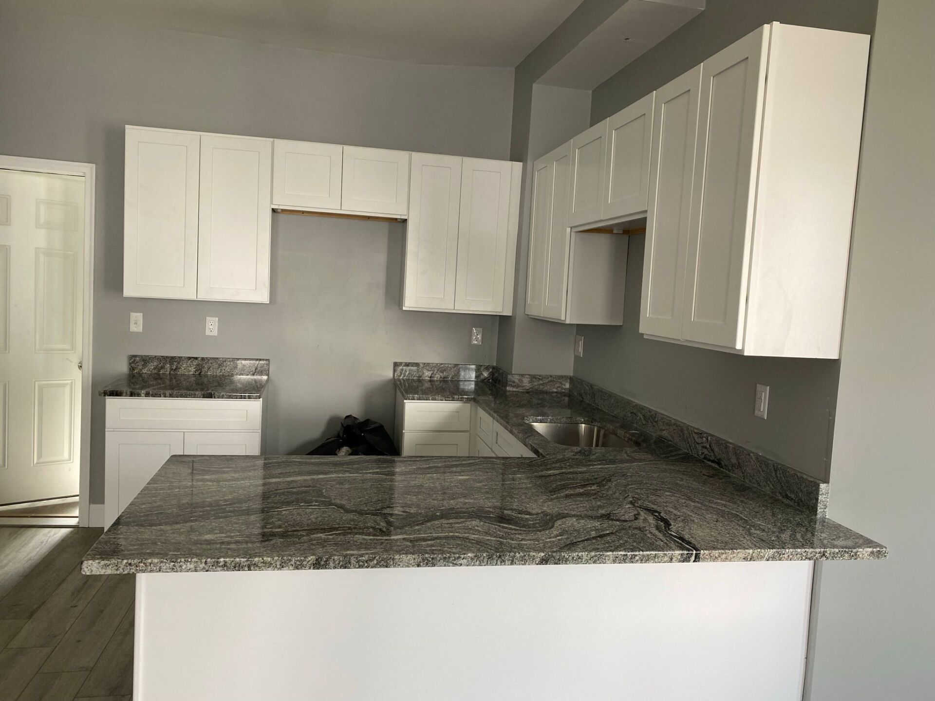 An empty kitchen with white cabinets and granite counter tops.