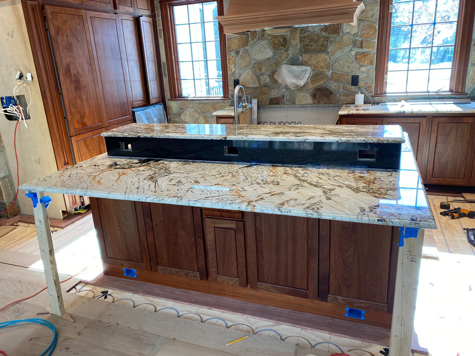 A kitchen with a granite counter top and wooden cabinets under construction.