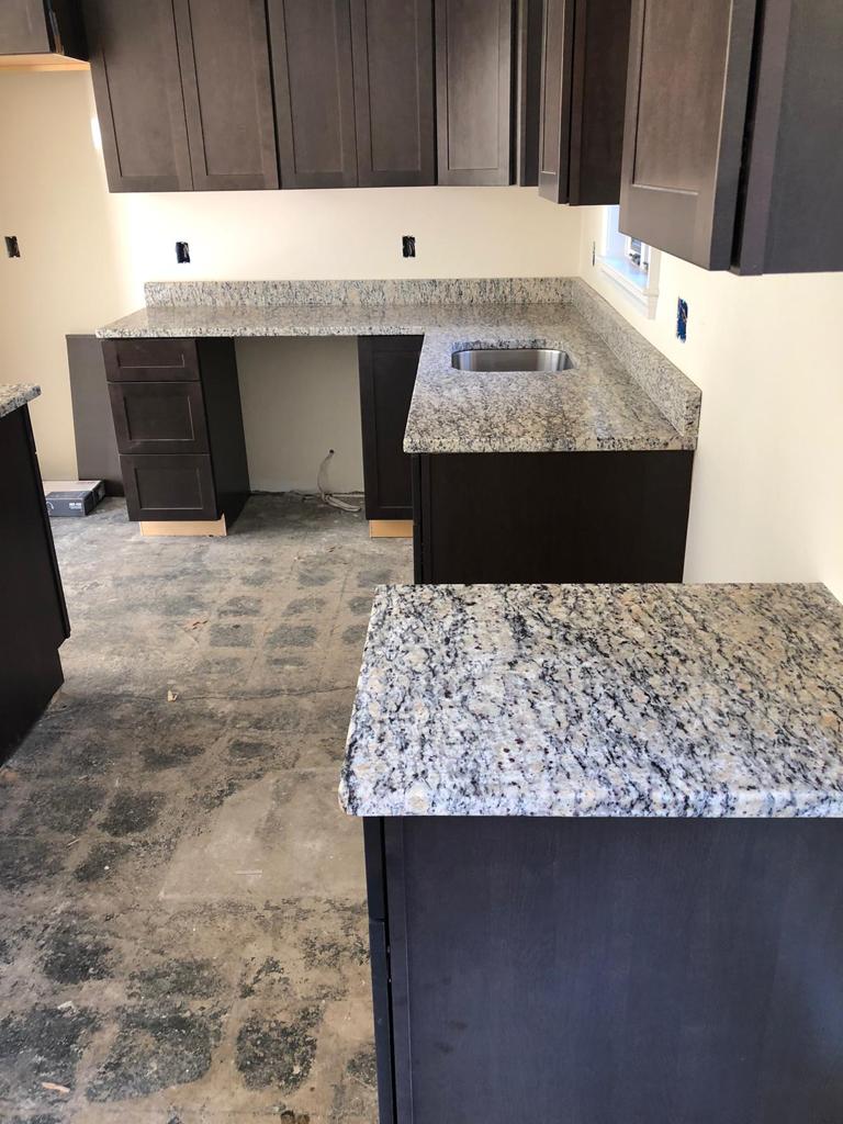 A kitchen with granite counter tops and black cabinets