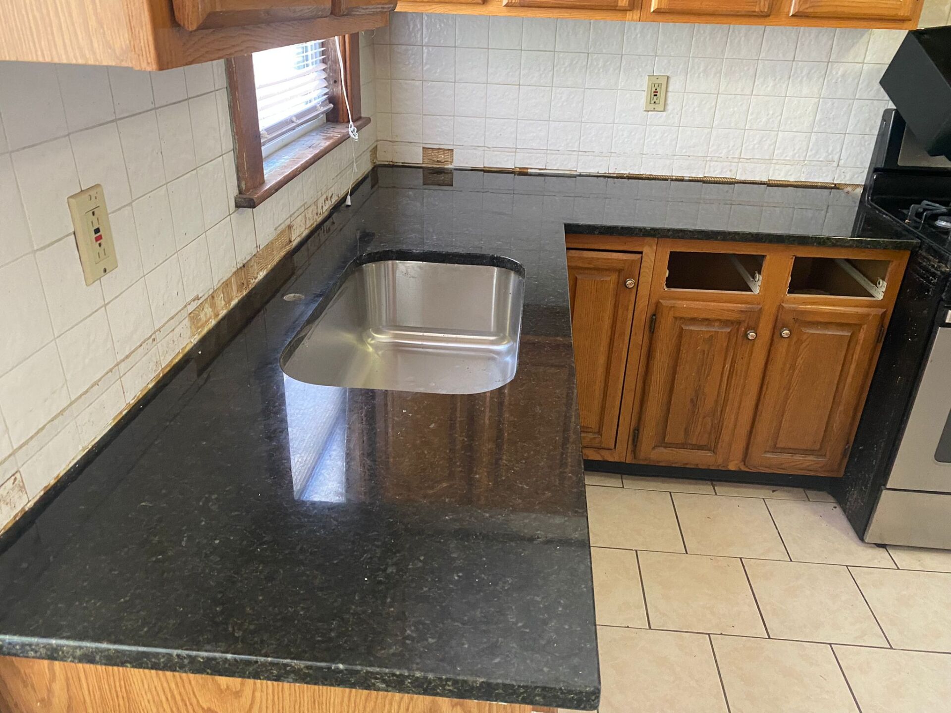 A kitchen with a black counter top and a stainless steel sink